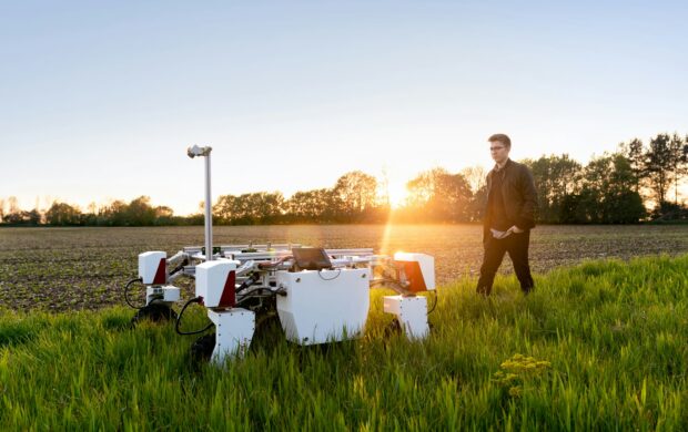 man in brown shirt standing on green grass field during sunset